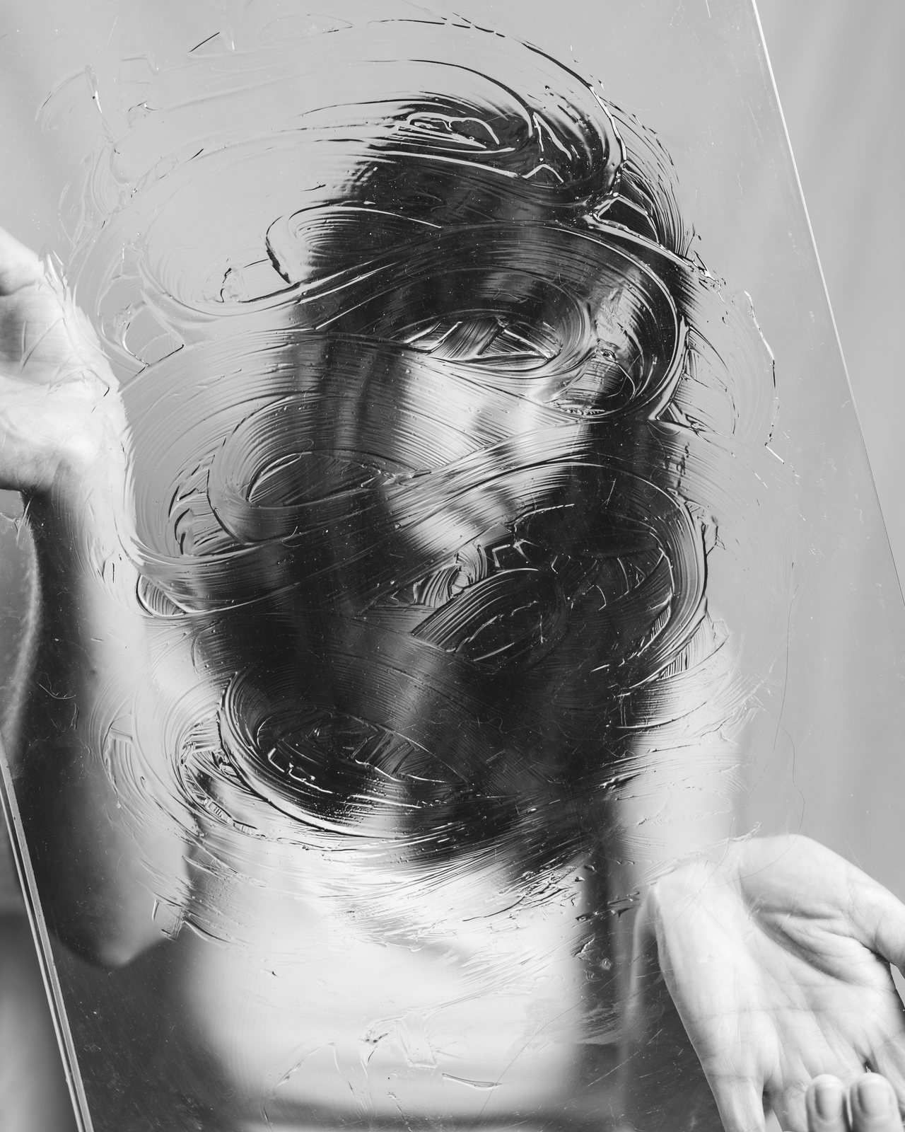 Pam Conde creando un autorretrato en blanco y negro por capas tras una superficie transparente pintada