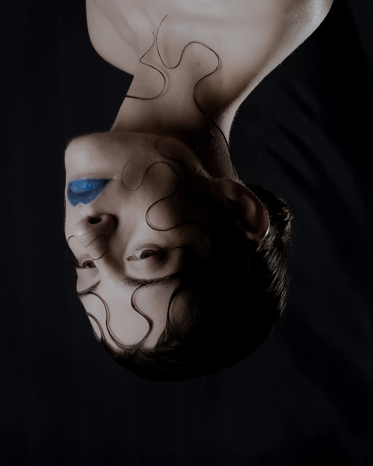 Upside-down self-portrait with blue lips reflected in a mirror