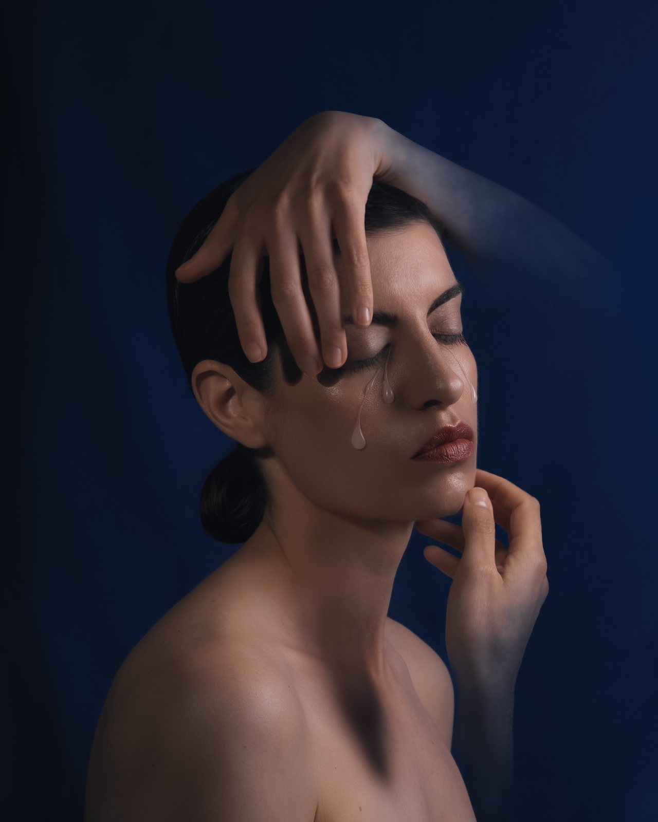 Self-portrait with overlapping hands and translucent tears